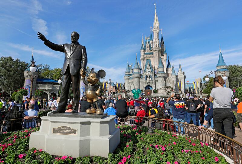A statue of Walt Disney and Micky Mouse stands in front of the Cinderella Castle at the Magic Kingdom at Walt Disney World in 2019.