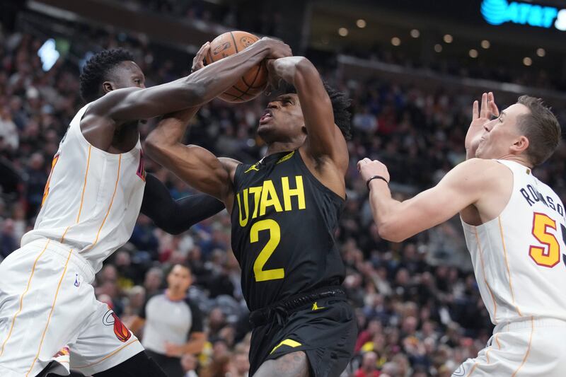 Utah Jazz guard Collin Sexton (2) is fouled by Miami Heat guard Victor Oladipo, left, as forward Duncan Robinson (55) watches during the second half of an NBA basketball game Saturday, Dec. 31, 2022, in Salt Lake City.