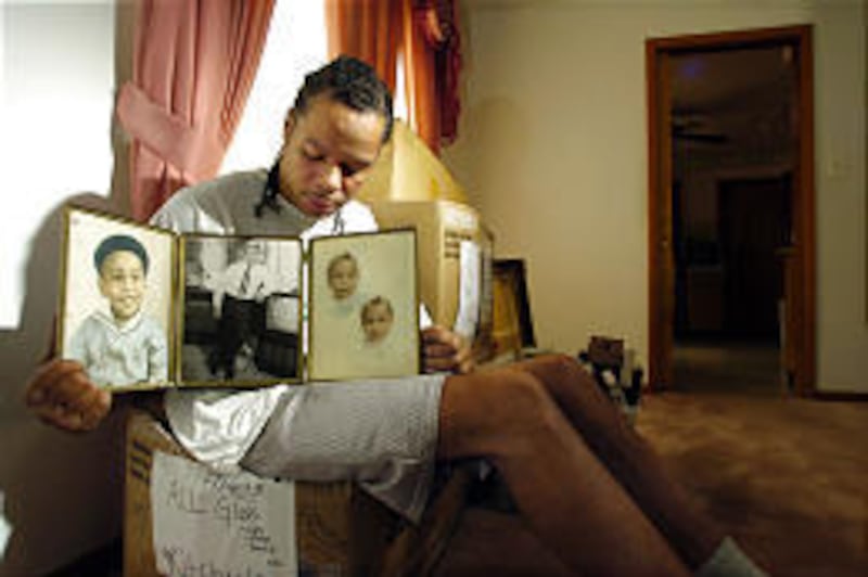 Abriel Thomas, a cousin of Emmett Till, holds a triptych showing childhood photos of Till in his home in Chicago Monday.