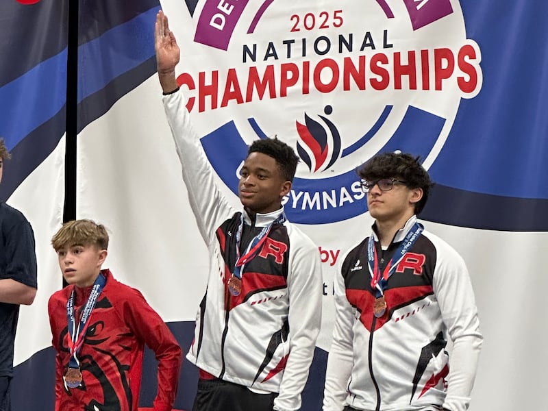 Bentley Watson raises his right arm in the air showing the "gymnastics salute," as he receives a medal at the 2025 national championships in Salt Lake City, Utah in May 2025.