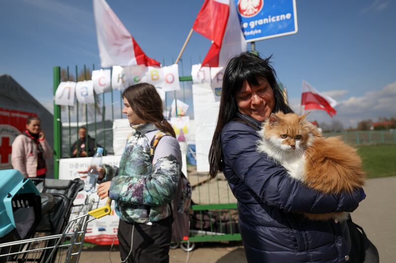 Helen Shumska, from Kharkiv, Poland, holds Rigik as they cross the Polish-Ukrainian border into Medyka, Poland, on Wednesday, April 20, 2022.