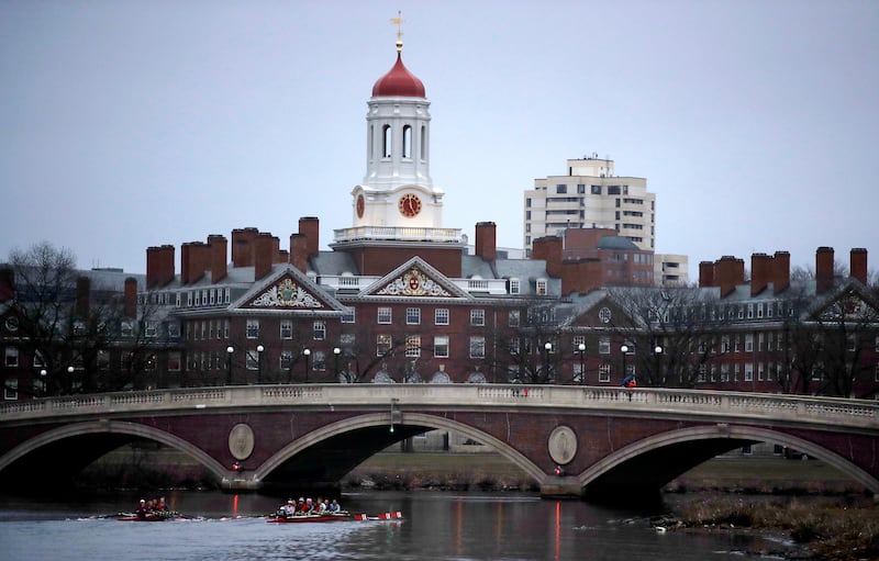 In this March 7, 2017, file photo, rowers paddle down the Charles River past the campus of Harvard University in Cambridge, Mass. A lawsuit alleging racial discrimination against Asian-American applicants in Harvard's admissions process is heading to tria