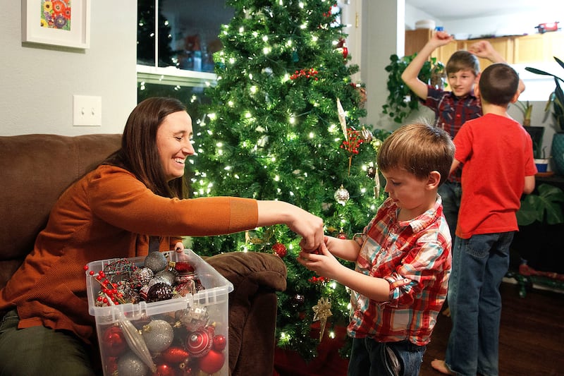 Heather Aliano, left, decorates the Christmas tree with her sons Vincent, 4, Ethan, 12, and Mason, 10, on Wednesday, Nov. 28, 2018, at their home in Bellevue, Nebraska. Aliano, a mother of four, limits the number of gifts her children receive at Christmas
