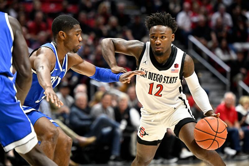 San Diego State guard Darrion Trammell (12) drives past BYU guard Rudi Williams (3) during the first half of an NCAA college basketball game Friday, Nov. 11, 2022, in San Diego. (AP Photo/Denis Poroy)