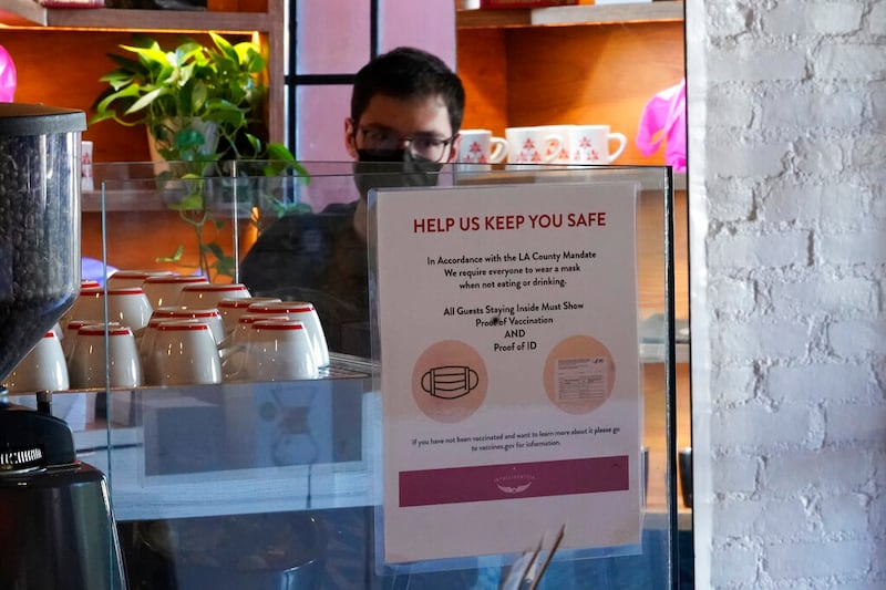 A sign explaining the Los Angeles County vaccine mandate is posted inside a coffee shop.