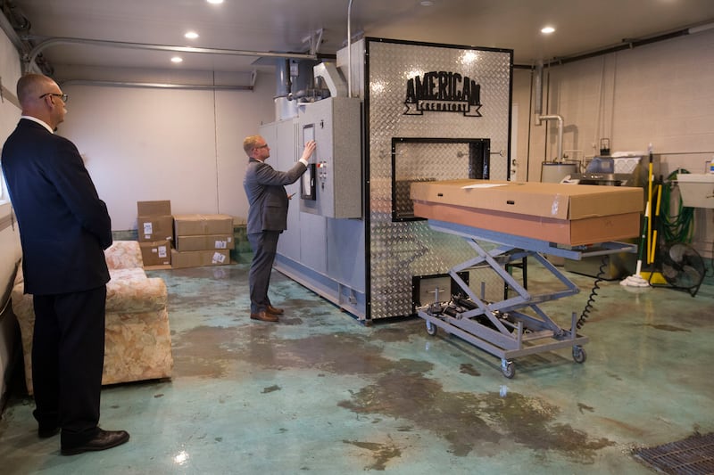 Boomer Benson, left, and Cole Houghton, owner of Tate Mortuary, prepare to cremate a body at the mortuary in Tooele in June 2018. Houghton has ordered an alkaline hydrolysis machine, making him the only mortician in Utah who will have the ability to offer