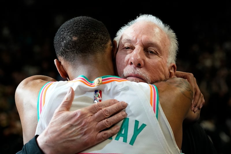 San Antonio Spurs coach Gregg Popovich is hugged by guard Dejounte Murray