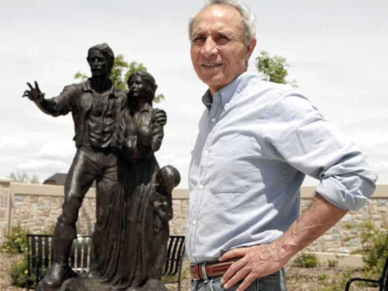 Erasmo Fuentes stands in the pioneer cemetery in Spanish Fork with the statue he made of a pioneer family.