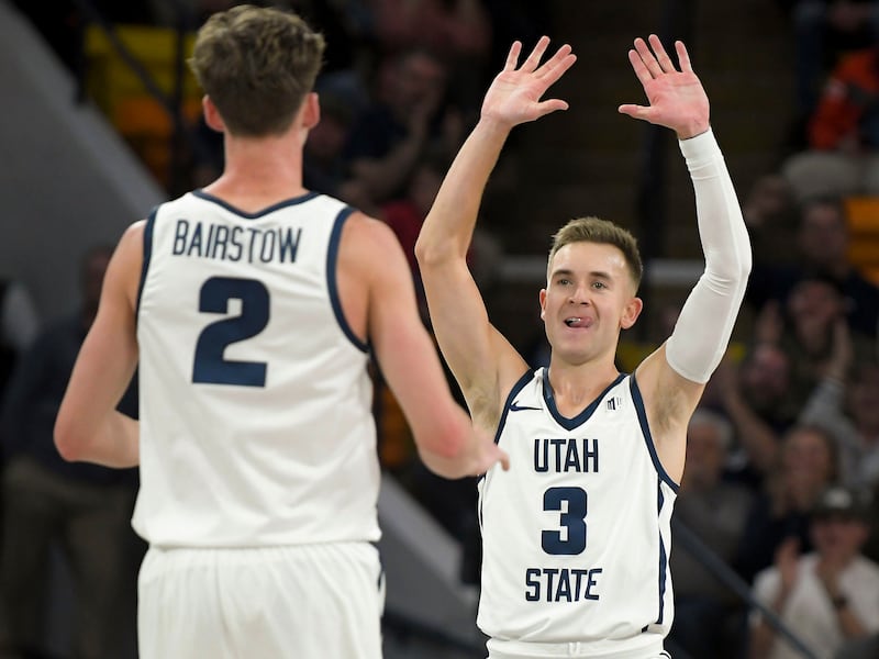 Utah State’s Sean Bairstow (2) celebrates with Steven Ashworth after a 3-pointer vs. Wyoming Jan. 10, 2023, in Logan, Utah.