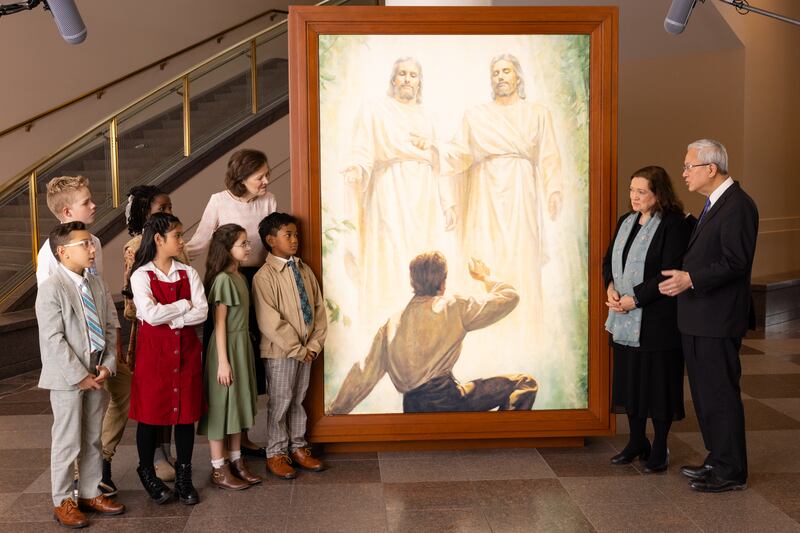 Elder Gerrit W. Gong, Sister Susan Gong, and President Susan H. Porter talk with six children by a portrait of the First Vision in the Conference Center in Salt Lake City during the filming of the Friend to Friend, released Sunday, May 24, 2026.