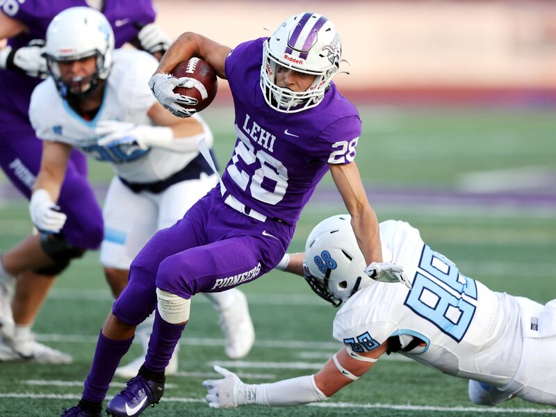 Lehi’s Carson Gonzalez (28) avoids Salem Hills’ Jackson Eyre (88) on a run during a football game at Lehi.