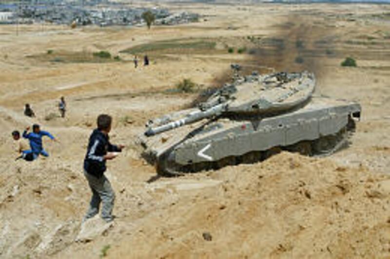 Palestinian youths throw stones at a tank during clashes with Israeli soldiers Tuesday as tanks and a bulldozer raided an area in the Gaza Strip. Four Palestinians died in several clashes.