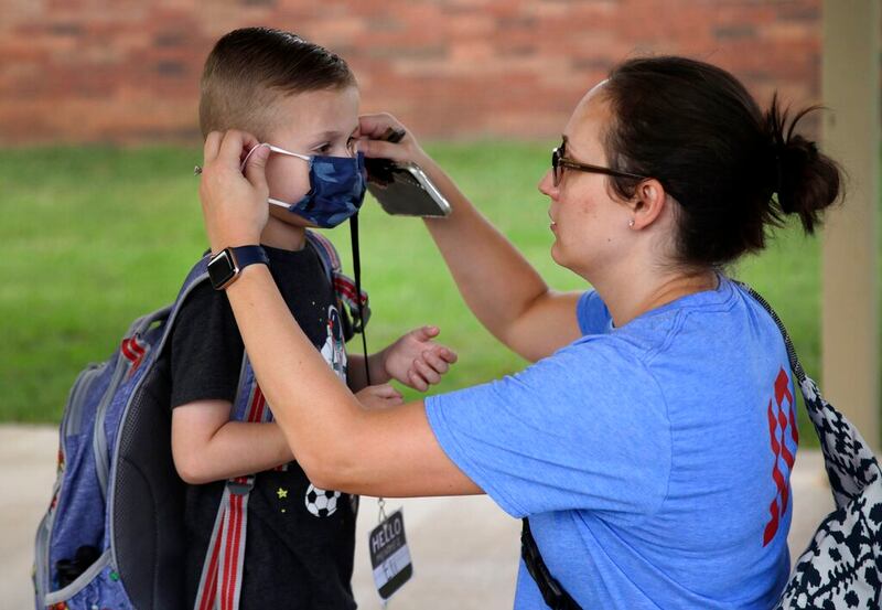 Emily Jeter helps her son Eli, a kindergarten student, get his mask in Tulsa, Okla.