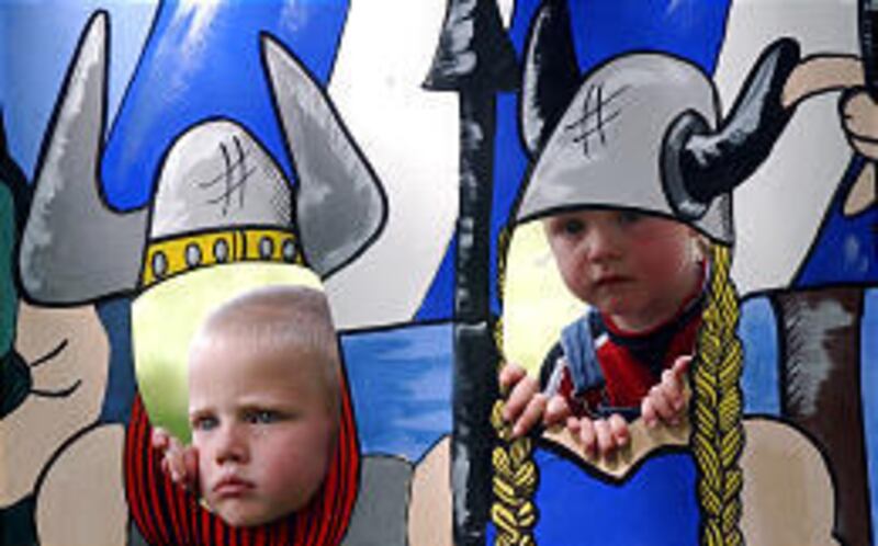 Dane, left, and Seth Robertson peer through Viking ship cutout at '02 festival.