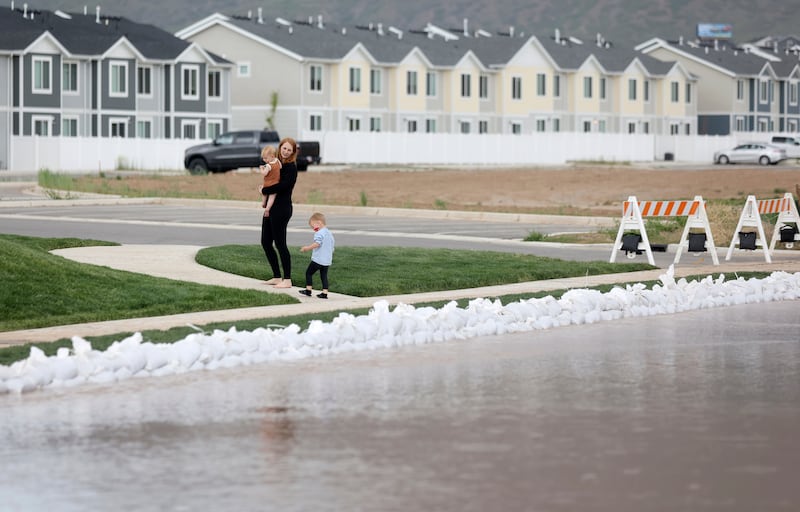 A woman and children walk near flooding in Santaquin on Wednesday, May 17, 2023.