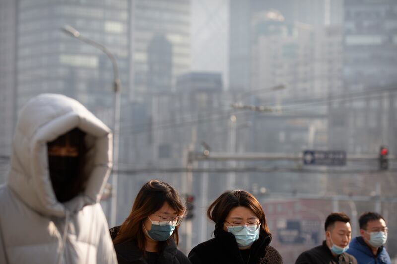 People wearing face masks to protect against the spread of the coronavirus walk across an intersection in Beijing, Wednesday, Jan. 20, 2021. China is now dealing with coronavirus outbreaks across its frigid northeast, prompting additional lockdowns and travel bans.
