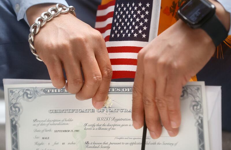 A refugee holds an American flag and Certificate of Naturalization during a naturalization ceremony for 14 refugees at the Capitol during World Refugee Week in Salt Lake City on Tuesday, June 15, 2021.