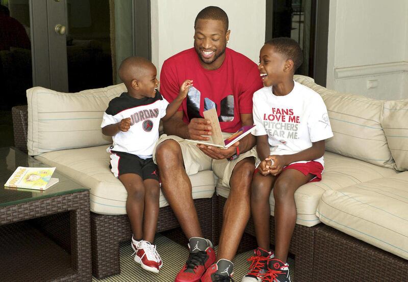 In this photo taken June 17, 2011 and released by the Wade family, Miami Heat basketball player Dwyane Wade and his sons, Zion, 4, left, and Zaire, 9 share a laugh over a book in their home in Miami Beach, Fla. This is a Father's Day weekend like none oth