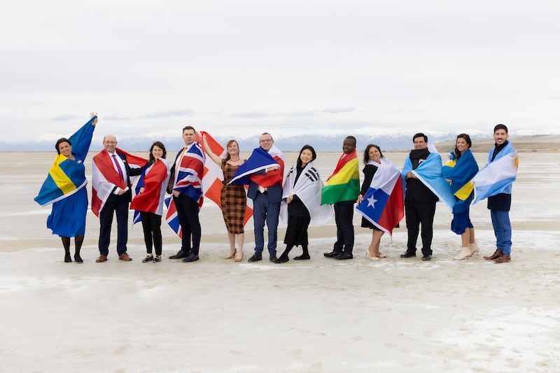 The 12 global participants of The Tabernacle Choir at Temple Square pose with their home country's flags on the salt flats.