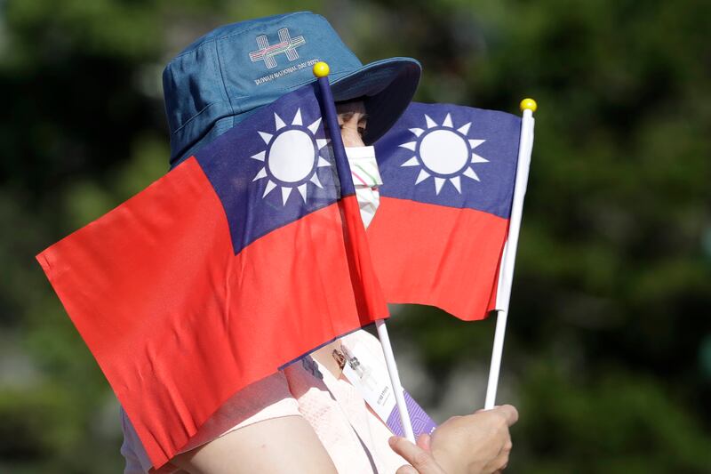 In this Oct. 10, 2021, file photo, a woman holds up Taiwan national flags during National Day celebrations in Taipei, Taiwan.