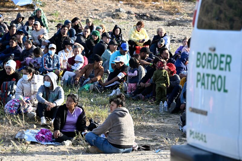 Asylum-seekers wait between the double fence on U.S. soil along the U.S.-Mexico border near Tijuana, Mexico.