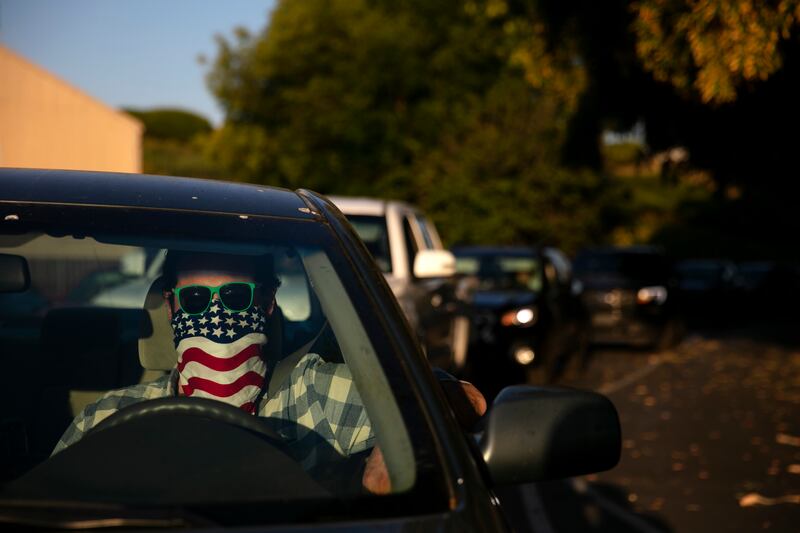 Charles McNulty wears a face covering while waiting in his car to purchase a movie ticket at Mission Tiki drive-in movie theater in Montclair, Calif., Thursday, May 28, 2020. California moved to further relax its coronavirus restrictions and help the battered economy. Flea markets, swap meets and drive-in movie theaters can resume operations. (AP Photo/Jae C. Hong)