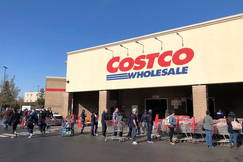 In this March 20, 2020, file photo, shoppers line up to enter a Costco store in Tacoma, Wash. Americans are beginning to see the first economic impact payments hit their bank accounts this week. The IRS tweeted Saturday, April 11, 2020, that it had begun depositing funds into taxpayers’ bank accounts and would be working to get them out as fast as it can. (AP Photo/Ted S. Warren, Fle)