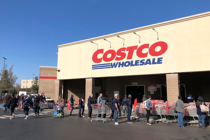In this March 20, 2020, file photo, shoppers line up to enter a Costco store in Tacoma, Wash. Americans are beginning to see the first economic impact payments hit their bank accounts this week. The IRS tweeted Saturday, April 11, 2020, that it had begun depositing funds into taxpayers’ bank accounts and would be working to get them out as fast as it can. (AP Photo/Ted S. Warren, Fle)