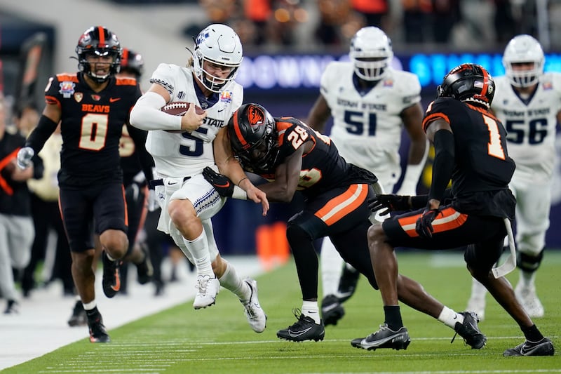 Utah State quarterback Cooper Legas (5) is pushed out of bounds by Oregon State defensive back Kitan Oladapo.
