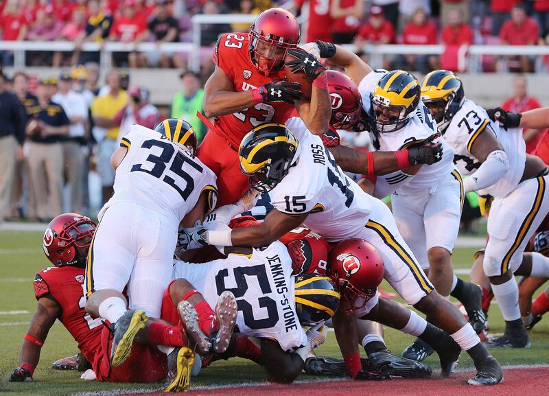 Utah Utes running back Devontae Booker (23) dives over Michigan for a touchdown.