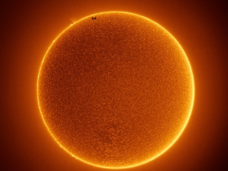 The photo meshes two photos together, one of the space station transiting the sun and another capturing the details of the sun’s actual surface.