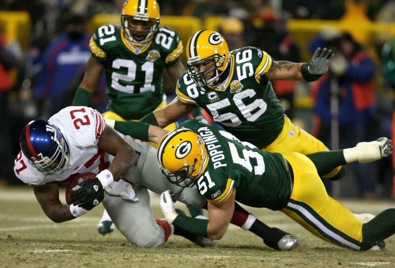 Runningback Brandon Jacobs (L) of the New York Giants is tackled by Brady Poppinga (51) and Nick Barnett (56) of the Green Bay Packers during the NFC championship game 20 January 2008 at Lambeau Field in Green Bay, Wisconsin.