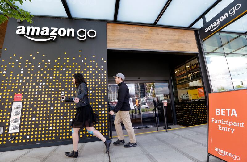 FILE - In this Thursday, April 27, 2017, file photo, people walk past an Amazon Go store in Seattle. Amazon Go shops are convenience stores that don't use cashiers or checkout lines, but use a tracking system that of sensors, algorithms, and cameras to de