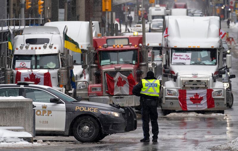Police man a barricade in front of vehicles parked as part of the trucker protest