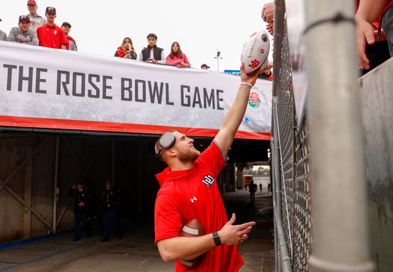 Utah Utes tight end Brant Kuithe hands a fan a signed ball.