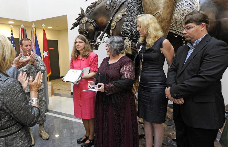 Joleen Cahill, second from left, holds the Army Award for Valor certificate presented to her by Army Brigadier General Joseph P. DiSalvo, left, during a ceremony to honor her husband Chief Warrant Officer Two (retired) Michael G. Cahill on Monday, May 23,