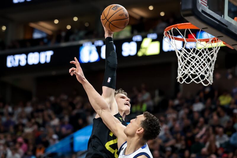 Dallas Mavericks center Dwight Powell (wearing white) is charged with a foul as Utah Jazz forward Lauri Markkanen (wearing black) goes for a dunk,