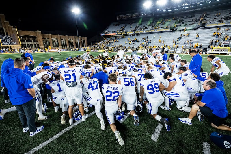 Wyoming and BYU football players kneel in prayer together after their game in Laramie, Wyoming, on Sept. 14, 2024.