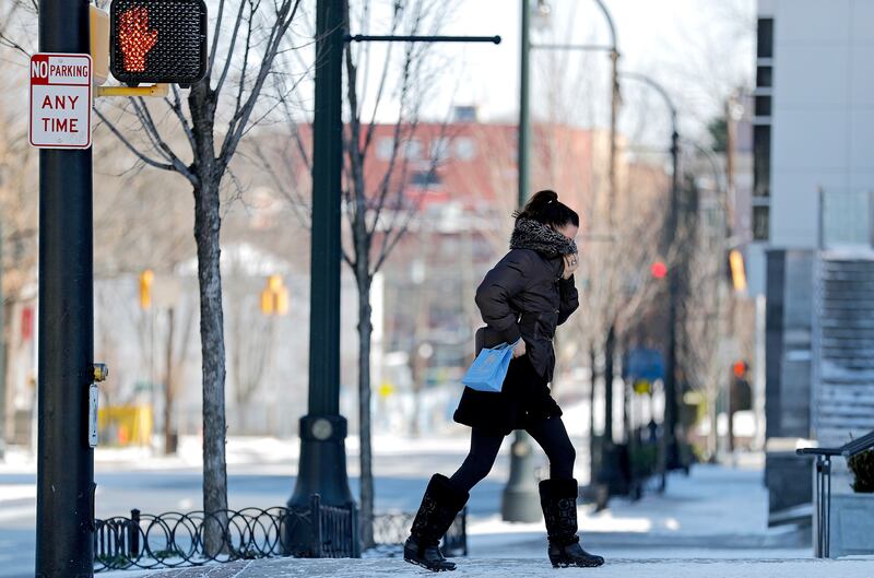 A pedestrian shields herself from the cold wind while walking in Atlanta, Wednesday, Jan. 17, 2018.