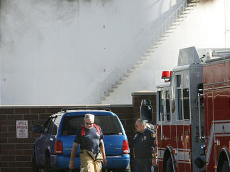 Fire crews pick up equipment at Silver Eagle Refinery on Tuesday. Four workers were injured in Monday's explosion.