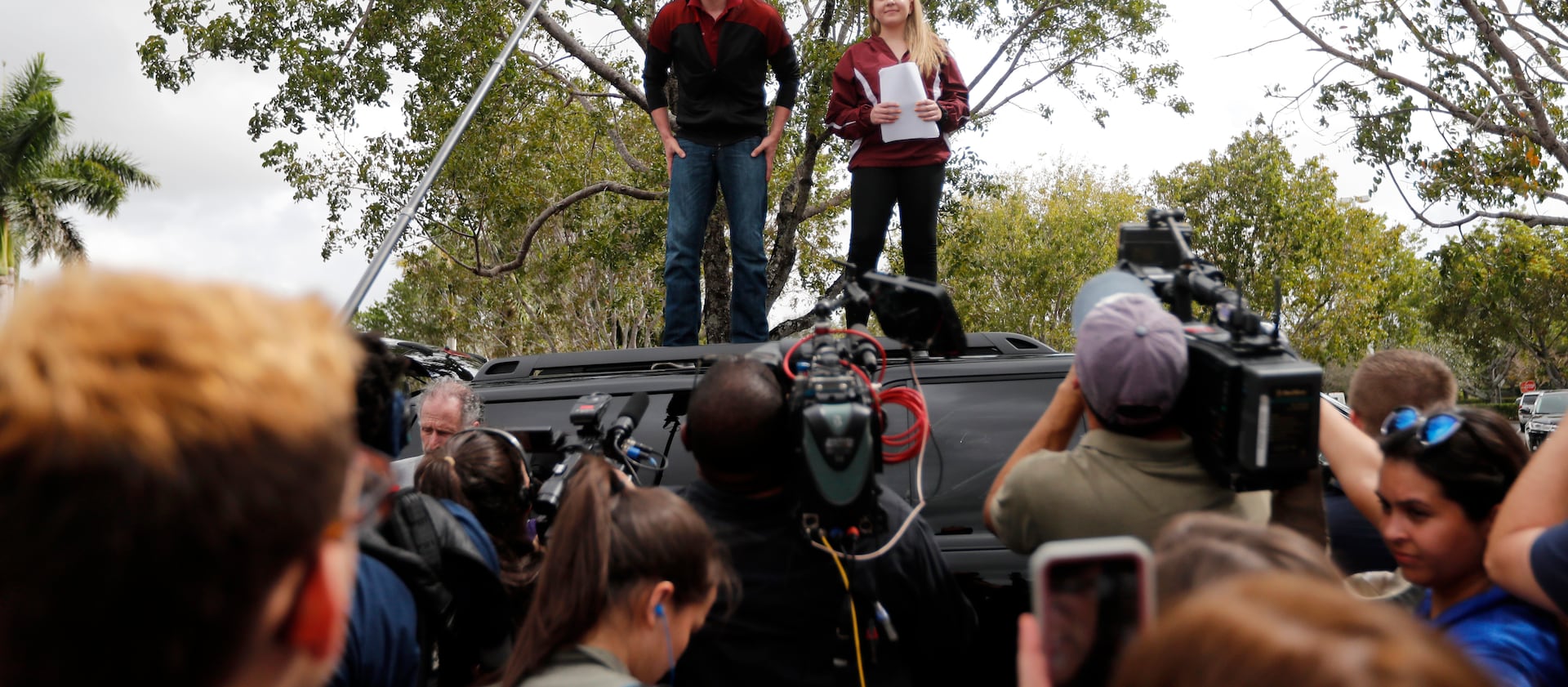Organizers Cameron Kasky, left, and Jackie Corin, student survivors from Marjory Stoneman Douglas High School address fellow students before boarding buses in Parkland, Fla., Tuesday, Feb. 20, 2018, to rally outside the state capitol.