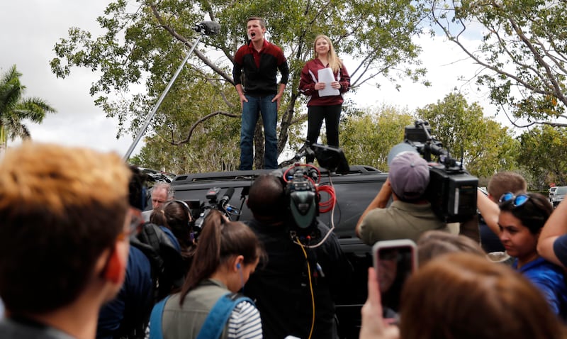 Organizers Cameron Kasky, left, and Jackie Corin, student survivors from Marjory Stoneman Douglas High School address fellow students before boarding buses in Parkland, Fla., Tuesday, Feb. 20, 2018, to rally outside the state capitol.