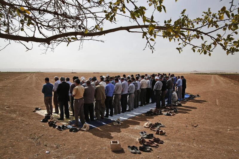 Turkish Kurds in the outskirts of Suruc, on the Turkey-Syria border, offer their Friday prayers as they gather to support Syrian Kurds over the border in nearby Kobani, Syria, where fighting between Syrian Kurds and the militants of Islamic State group in