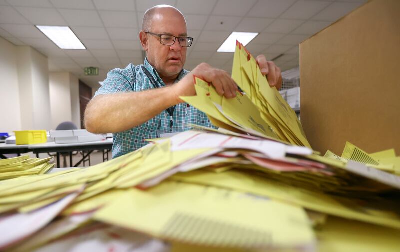 Elections coordinator Michael Fife gathers election envelopes at the Salt Lake County Government Center in Salt Lake City on Tuesday, Aug. 10, 2021.