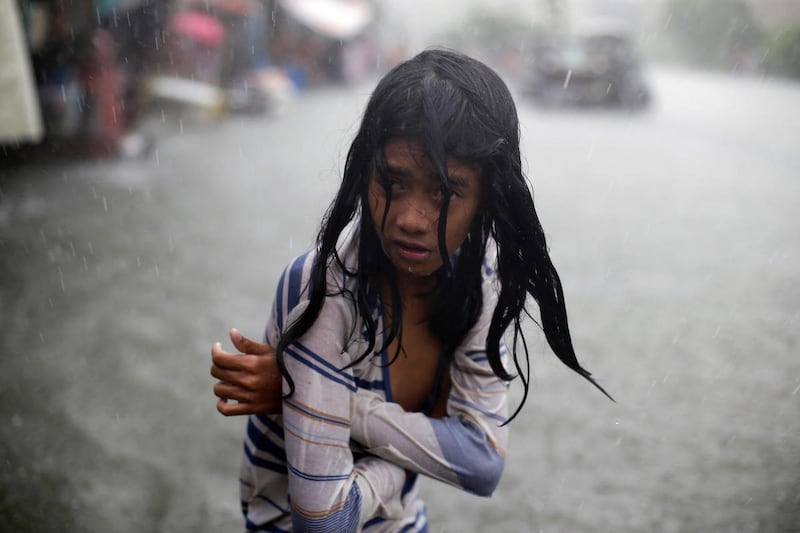 A Filipino girl tries to keep herself warm as she wades in floodwaters in the coastal village of Malabon, north of Manila, Philippines on Wednesday, July 8, 2015. Typhoon Chan-Hom is passing over the northeastern waters of the Philippines and heading to n