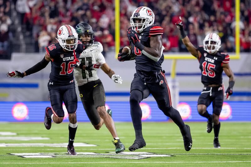 Utah Utes linebacker Devin Lloyd, wearing black, runs back an intercepted pass