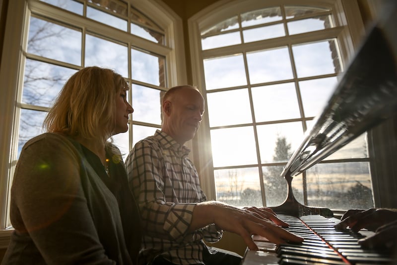 Jon and Michelle Schmidt are silhouetted as they sit and play the piano in their home in Provo on Friday, Nov. 24, 2017.