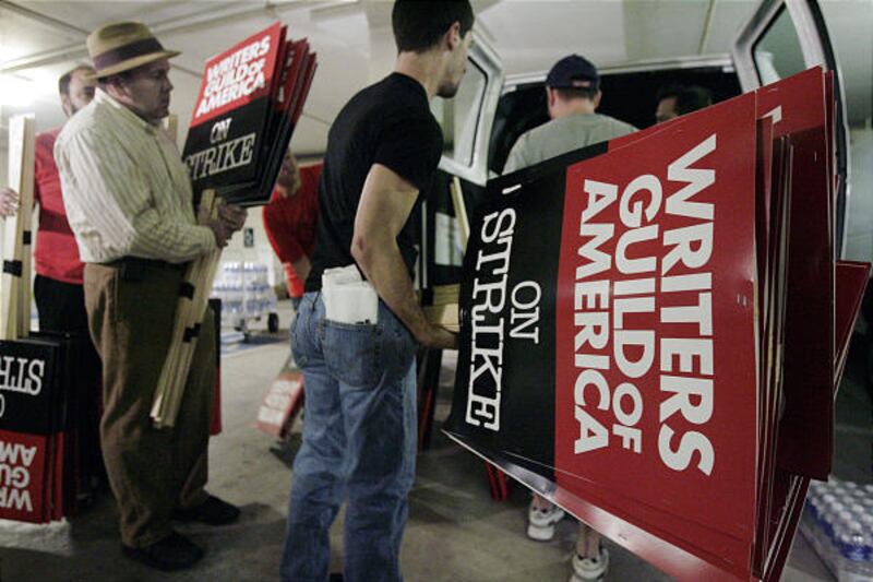 People load picket signs into vans at the Writers Guild of America headquarters.