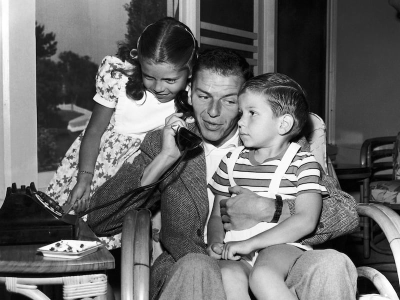 In this 1948 file photo, Frank Sinatra holds a telephone with his children, Nancy and Frank Jr., in the Hollywood area of Los Angeles. Frank Sinatra Jr., who carried on his famous father's legacy with his own music career, died unexpectedly of cardiac arr