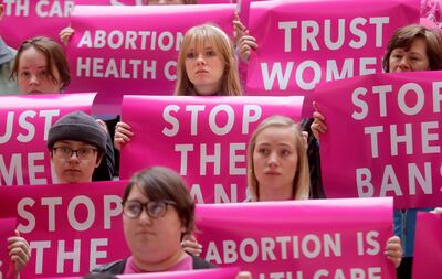 FILE - Audrey Meyer, top center, holds signs with other supporters during a press conference with Planned Parenthood Association of Utah and the ACLU of Utah Foundation to announce their plans to file a lawsuit against H.B. 136, the 18-week abortion ban p